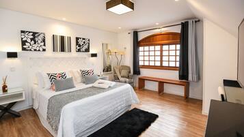 A modern bedroom with a large bed, bedside tables, a desk, and a window with curtains.