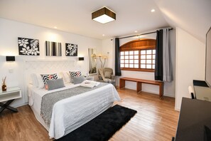 A modern bedroom with a large bed, bedside tables, a desk, and a window with curtains. - Pousada La Lavande (Gramado)