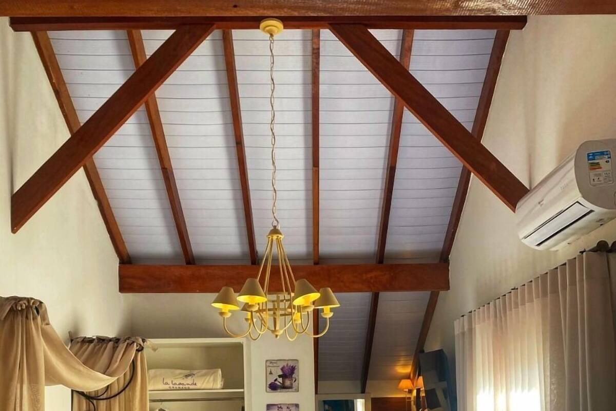 A bedroom with a bed, a chandelier, a wardrobe, and an air conditioning unit.