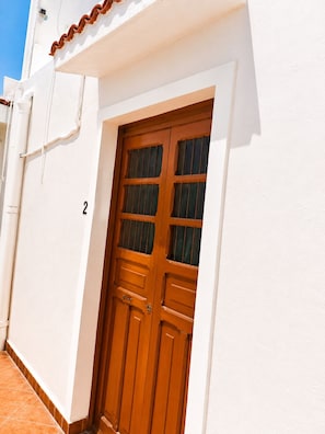 A white building with a wooden double door and a number '2' on the wall. - Guest House La Casa del Quetzal (Mérida)