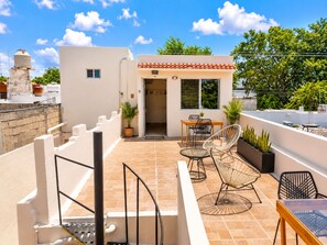 A rooftop terrace with a dining area, outdoor seating, and potted plants. - Guest House La Casa del Quetzal (Mérida)