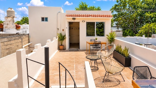 A rooftop terrace with a dining area, outdoor seating, and potted plants.