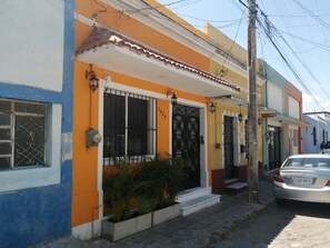 A residential building with a blue and orange facade, a gated entrance, and a parked car. - Guest House La Casa del Quetzal (Mérida)
