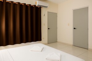 A hotel room with a bed, two doors, and an air conditioning unit. - Guest House La Casa del Quetzal (Mérida)