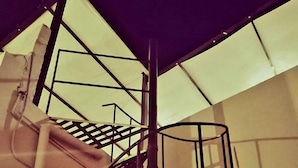 A spiral staircase with metal railings and a glass ceiling.