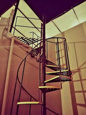 Una escalera en espiral con barandillas de metal y un techo de cristal.