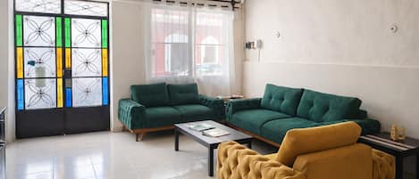 A living room with a green sofa, a yellow armchair, and a coffee table.