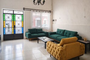 A living room with a green sofa, a yellow armchair, and a coffee table. - Guest House La Casa del Quetzal (Mérida)