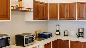 A kitchen with wooden cabinets, a microwave, a toaster, a blender, and a coffee maker.