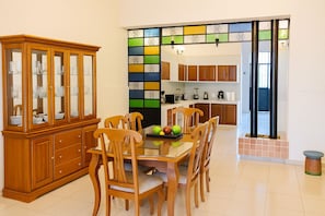 A dining area with a wooden cabinet, a glass-top table, and six chairs. - Guest House La Casa del Quetzal (Mérida)
