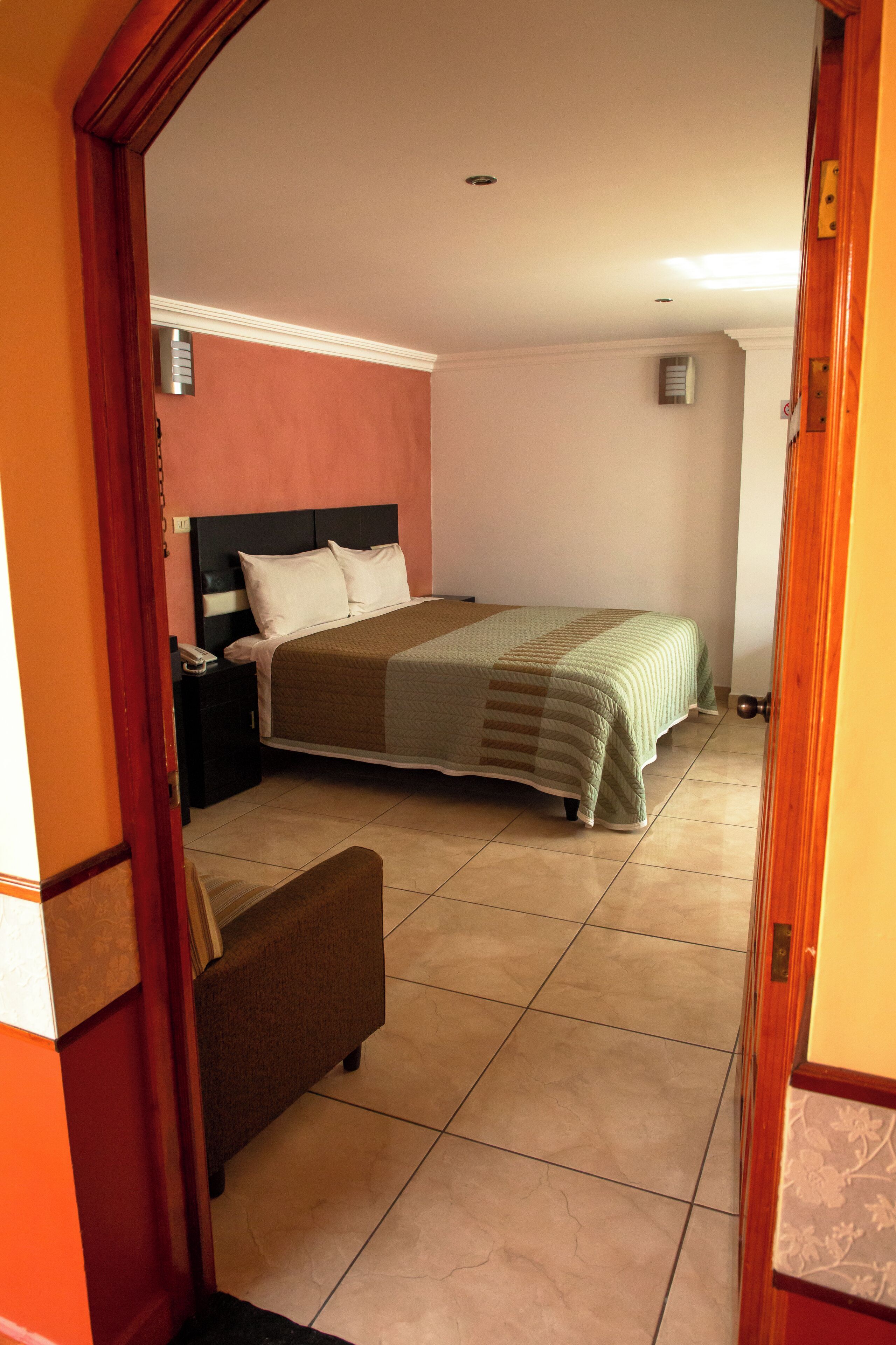 A bedroom with a bed, nightstand, and a chair.