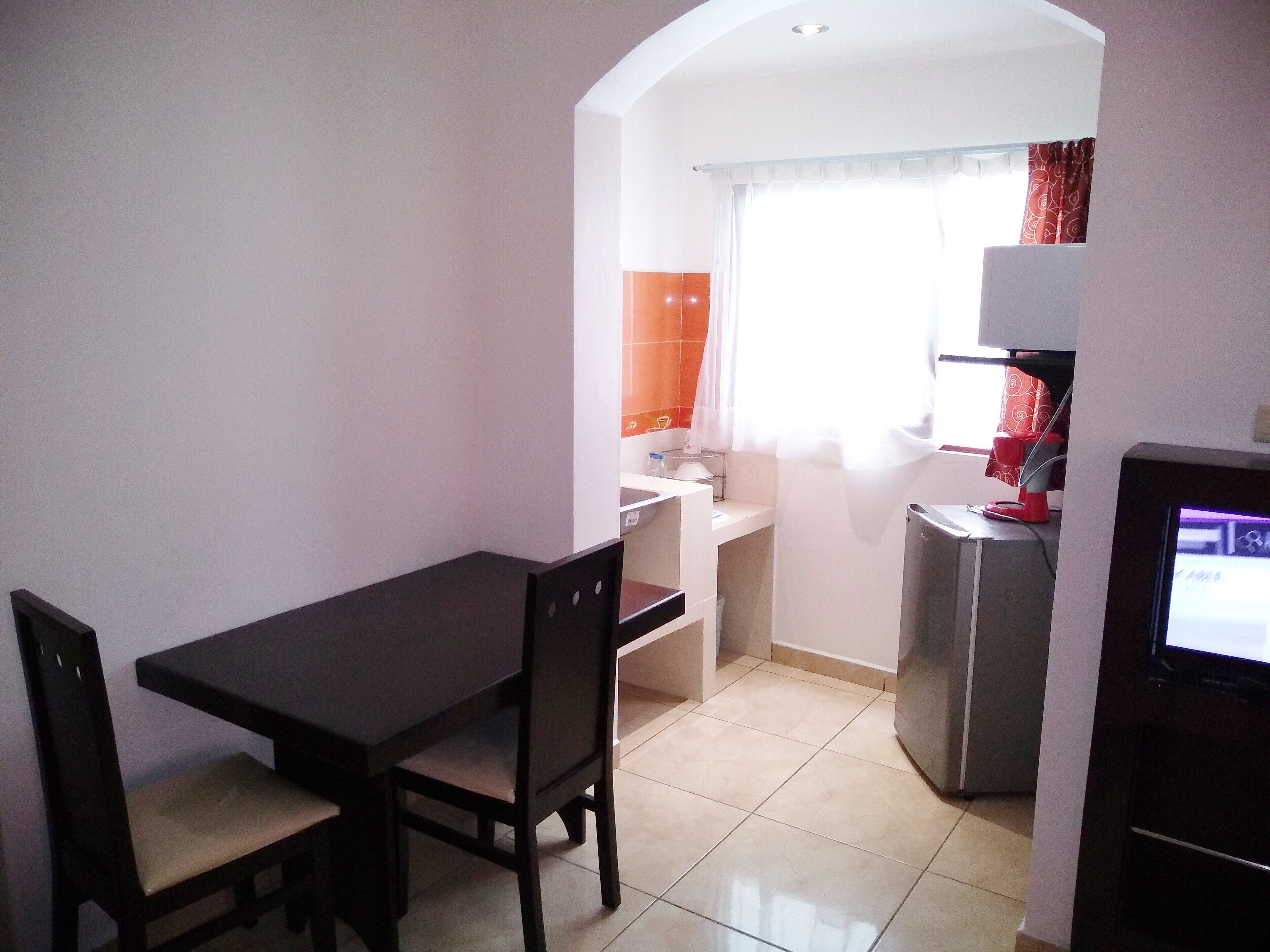 A compact kitchen with a dining area, a refrigerator, and a TV.
