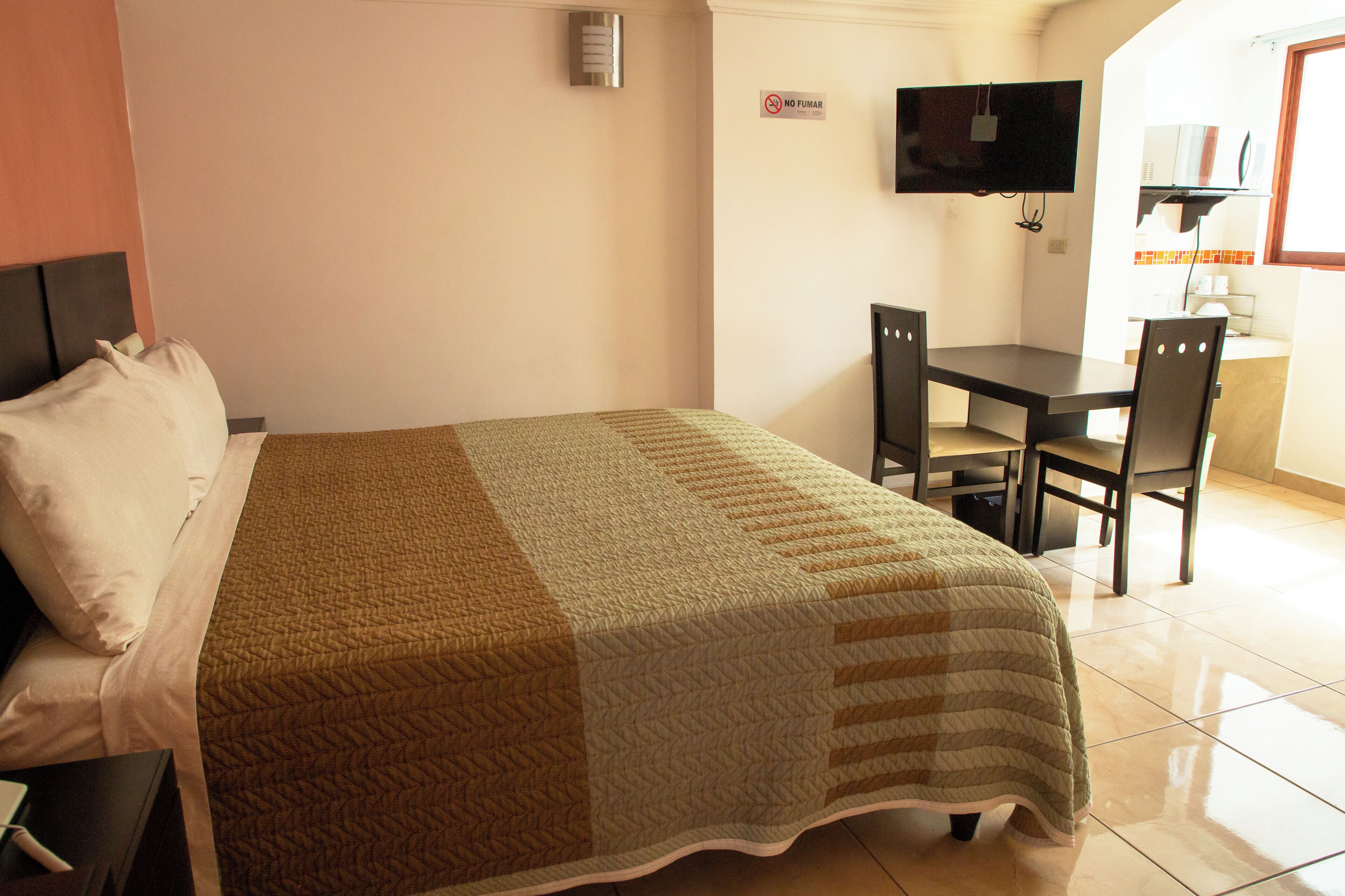 A hotel room with a bed, a desk, and a television.