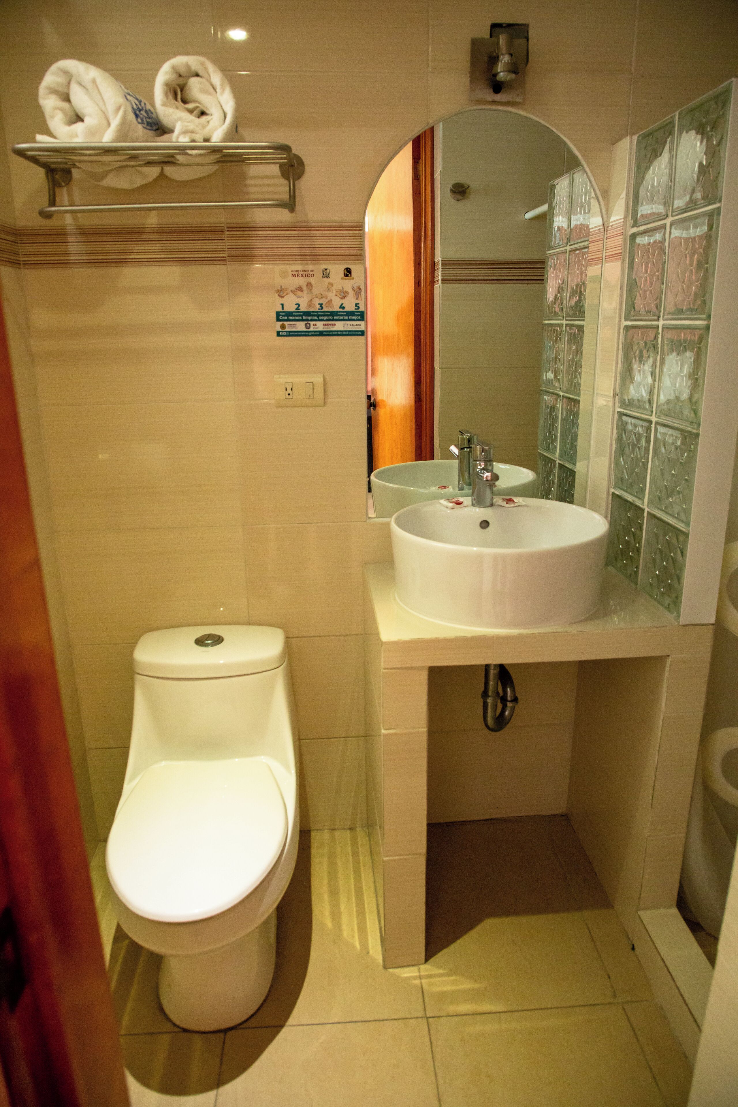 A compact bathroom with a toilet, sink, and mirror.