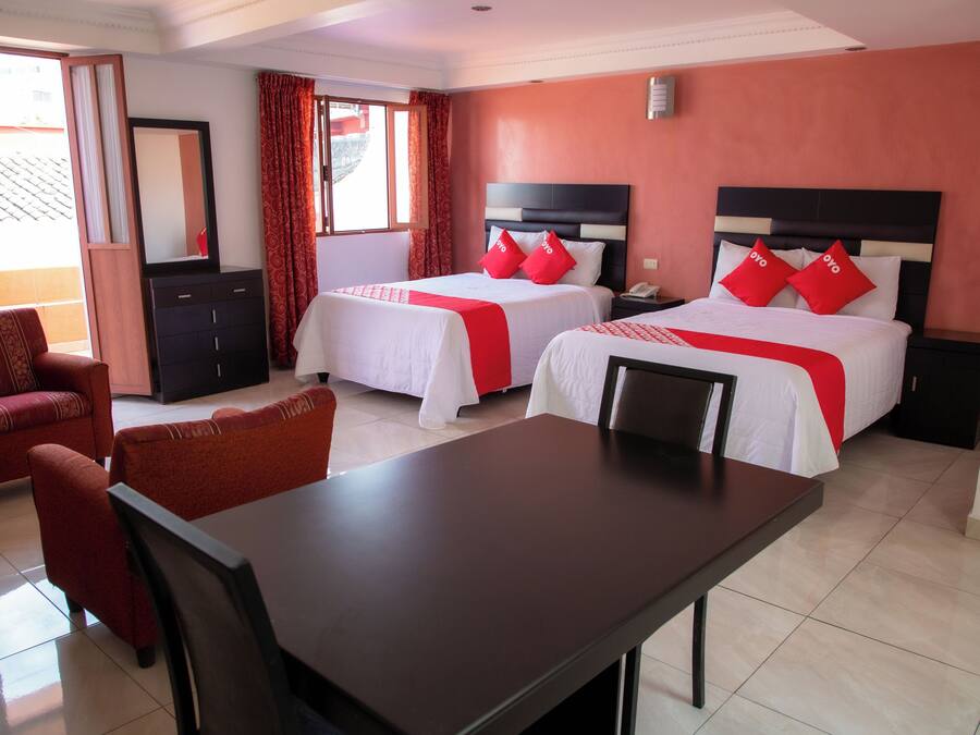 A hotel room with two beds, a desk, a chair, a wardrobe, and a window with curtains.