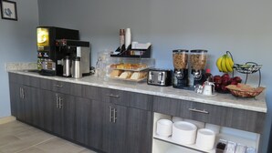 Una cocina con cafetera, tostadora, licuadora y diversos alimentos sobre la encimera.