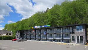 Un edificio de varios pisos con un letrero que dice "Rest Inn" y banderas de Estados Unidos, Canadá y la Unión Europea.