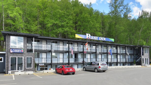 A multi-story building with a sign for 'Rest Inn' and a 'Lobby' entrance. There are two cars parked in front.