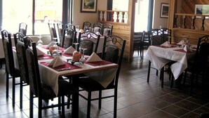 A restaurant with multiple tables set for dining, chairs, and a wooden interior. - Villager's Inn (Fruitvale)