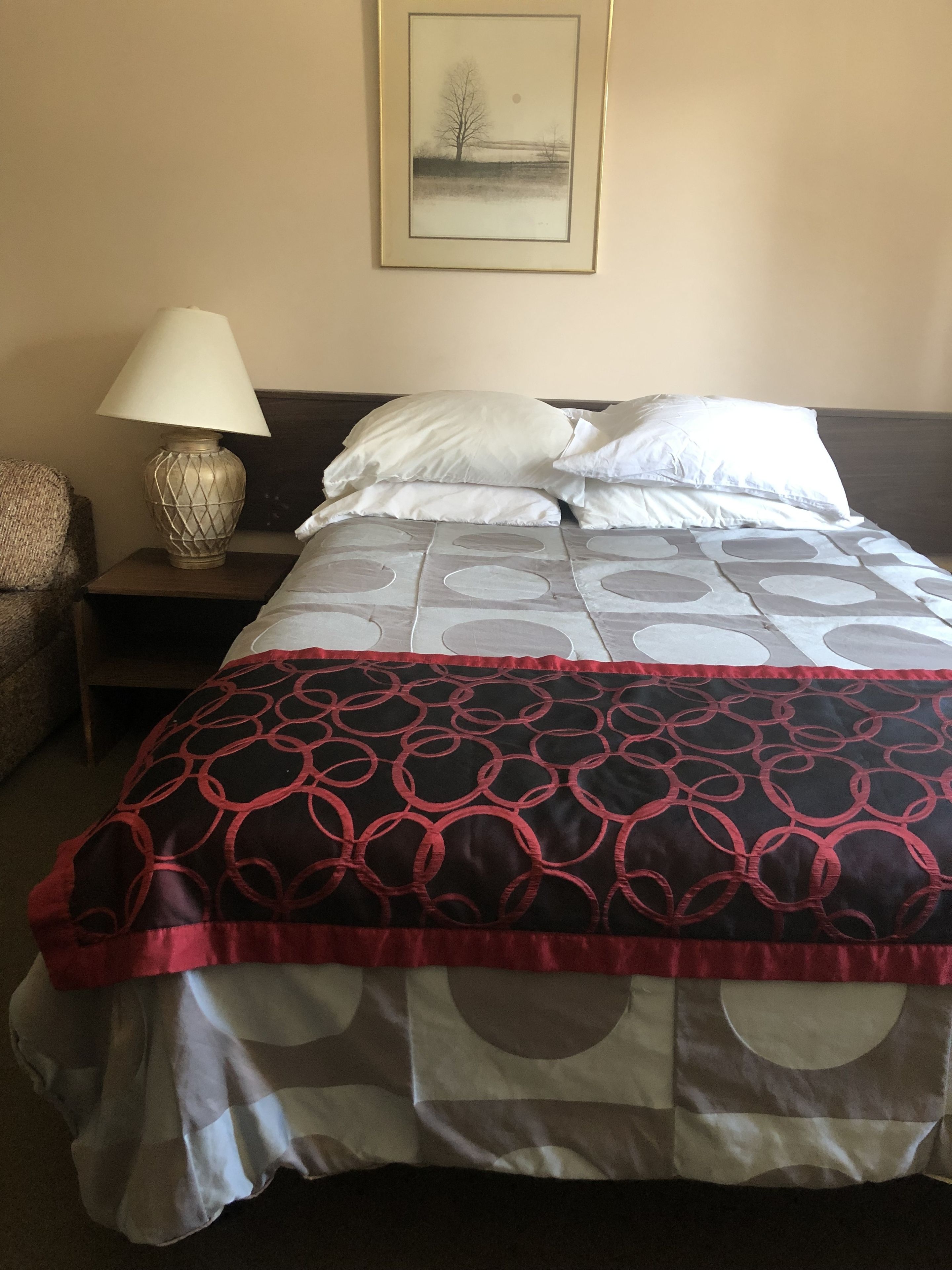 Una habitación de hotel con una cama, una mesita de noche, una lámpara y un cuadro en la pared.
