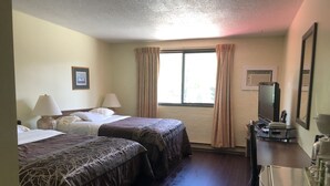 A hotel room with two beds, a desk with a mirror, a television, and a window with curtains. - Villager's Inn (Fruitvale)