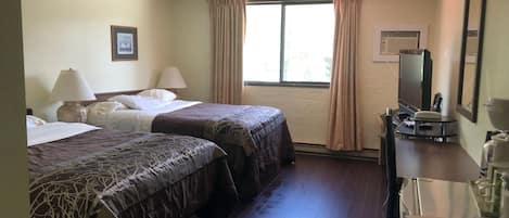 A hotel room with two beds, a desk with a mirror, a television, and a window with curtains.