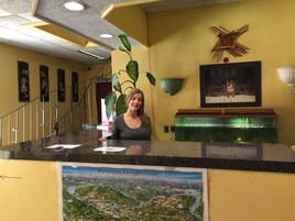 Un mostrador de recepción con un mapa de West Kootenay & Boundary Country, un reloj y una planta.