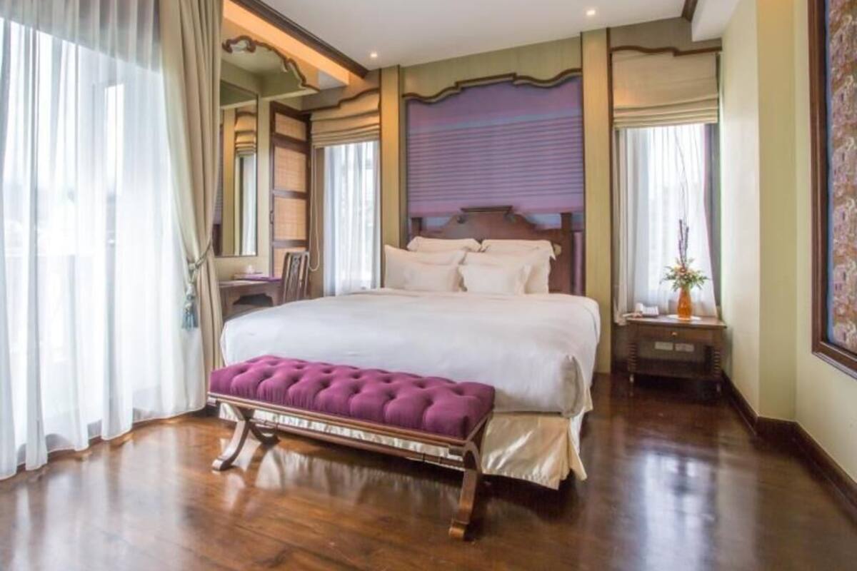 A spacious bedroom with a large bed, a bench, and a nightstand.