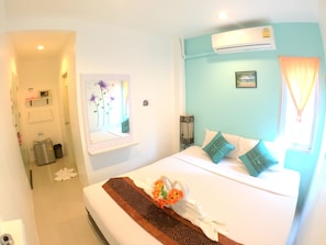 A hotel room with a bed, a wall-mounted air conditioner, a window with curtains, and a small bedside table with a lamp. - The Room Patong Hotel (Patong)