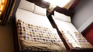 A double bed with a checkered bedspread and two pillows, a nightstand with a lamp, and a window with curtains. - Dalat Green City Hotel (Xuan Huong - Da Lat)