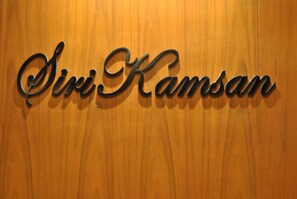 A wooden wall with a metal sign that reads "Siri Kamsan." - Sirikamsan House (Chiang Mai)