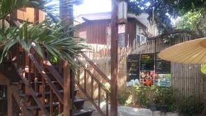 A wooden staircase leading to a building with a bamboo fence and a signboard advertising traditional Thai massage services. - Sirikamsan House (Chiang Mai)