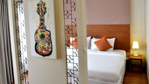 A hotel room with a bed, a nightstand, a lamp, and a colorful guitar painting on the wall. - Sirikamsan House (Chiang Mai)