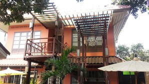 A two-story building with a balcony, a staircase, and a pergola with a chandelier. - Sirikamsan House (Chiang Mai)