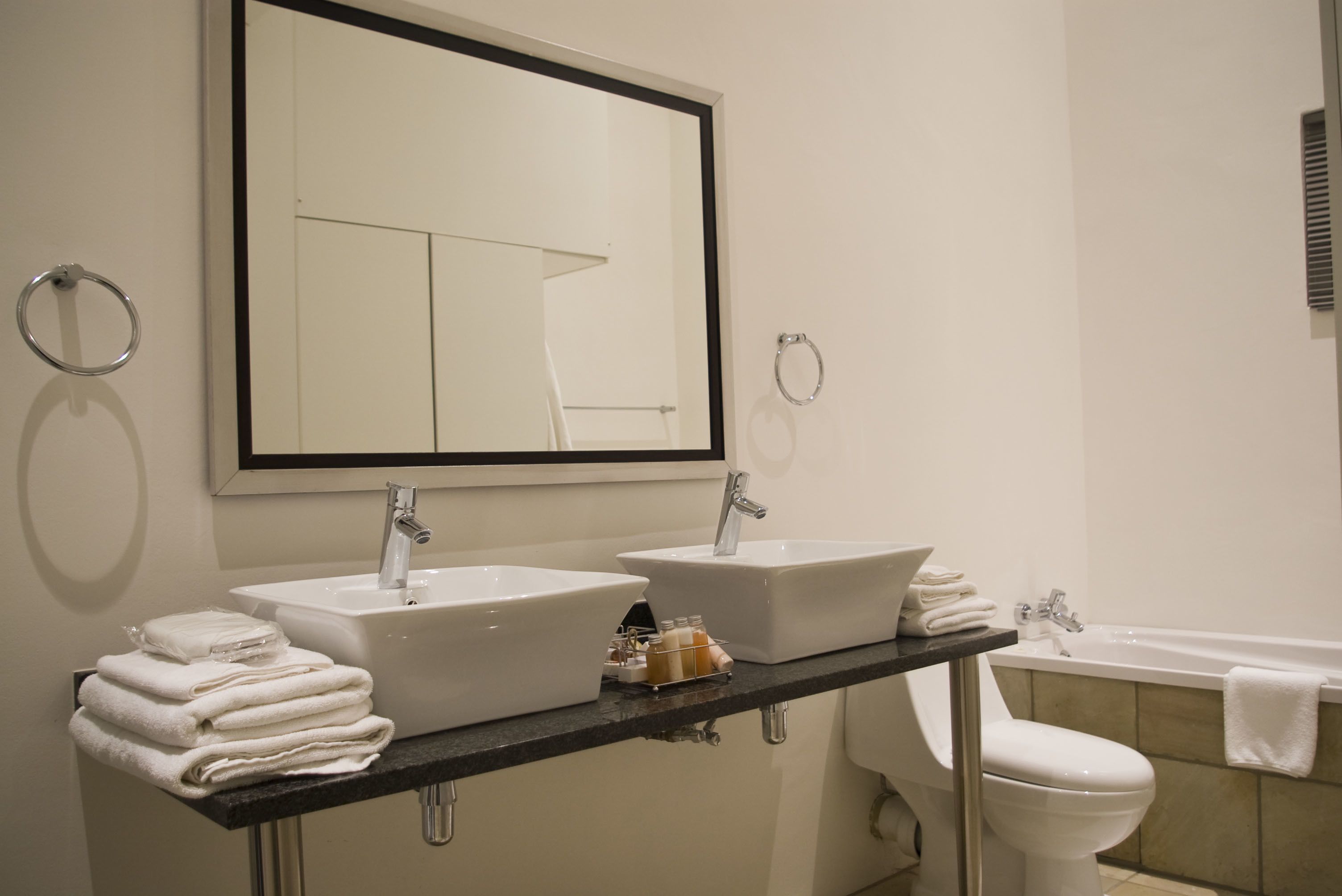 Une salle de bain avec deux lavabos, un miroir, des toilettes et une baignoire.