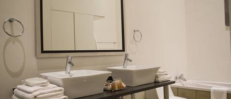Une salle de bain avec deux lavabos, un miroir, des toilettes et une baignoire.