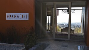 A building entrance with a sign reading "ORANGERIE" and a view of a cityscape through glass doors.