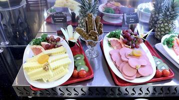 A buffet with various food items including fruits, cheeses, and meats.