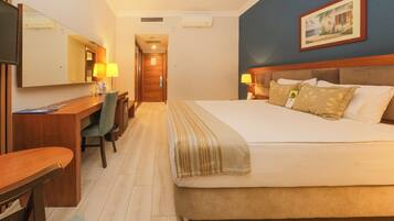 Una habitación de hotel con cama, escritorio, silla y un espejo grande.