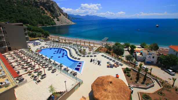 Um resort com uma piscina grande, espreguiçadeiras e vista para o mar.