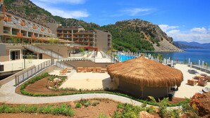 Um resort com piscina, área de estar externa e montanhas ao fundo.