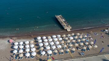 Playa privada, arena negra, sillas reclinables de playa, sombrillas