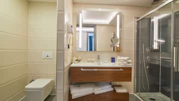 A modern bathroom with a toilet, vanity with a mirror, and a glass-enclosed shower.