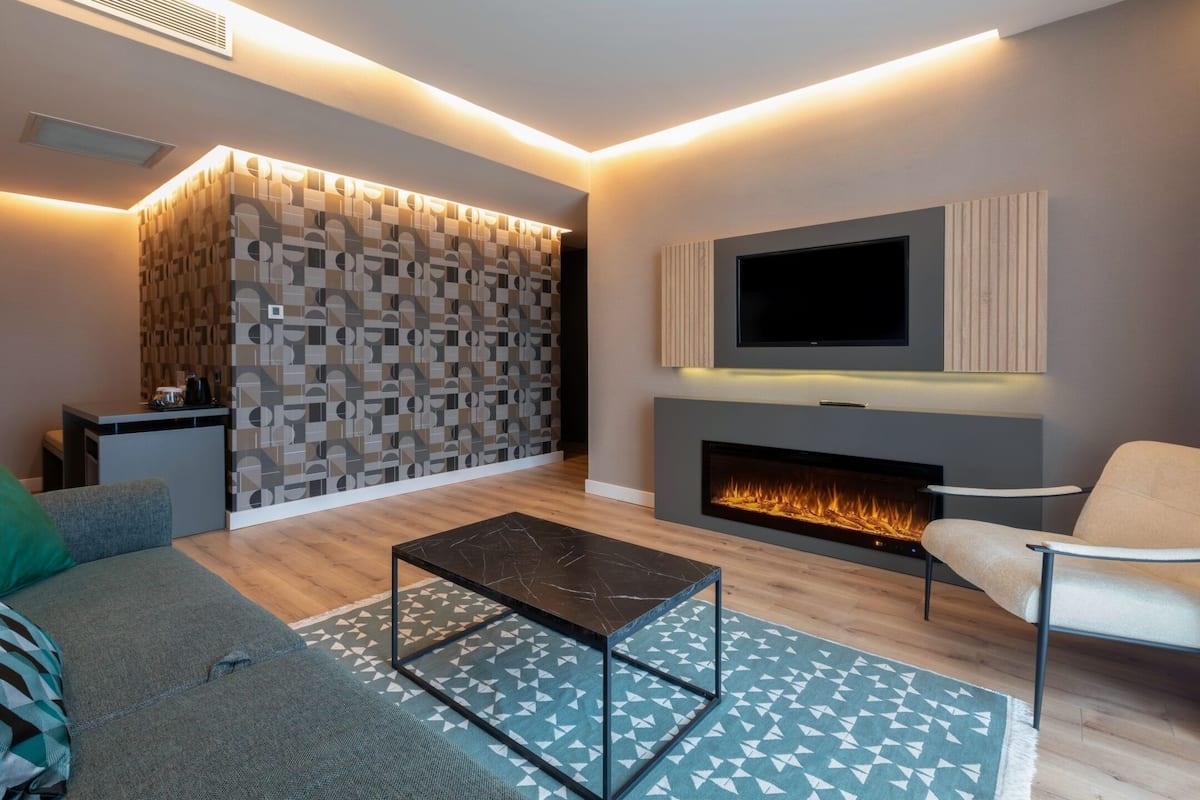 Una sala de estar moderna con chimenea, un televisor de pantalla plana y un papel tapiz estampado.