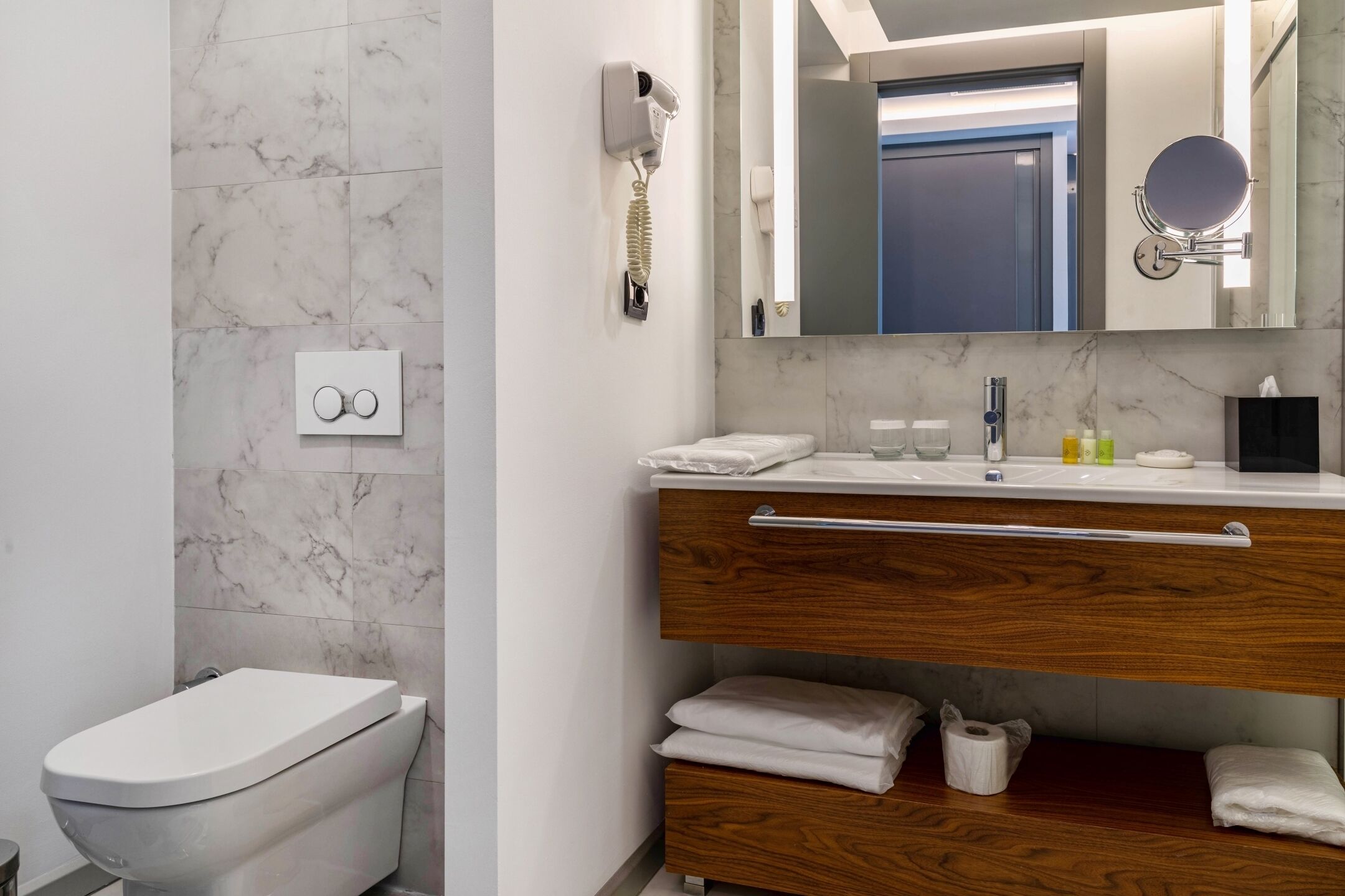 A modern bathroom with a toilet, a vanity with a mirror, and a towel rack.