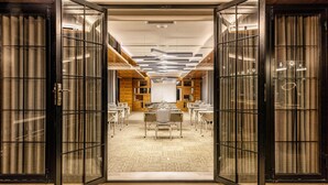 Un salón de conferencias con separaciones de vidrio, paneles de madera y una mesa central con sillas.