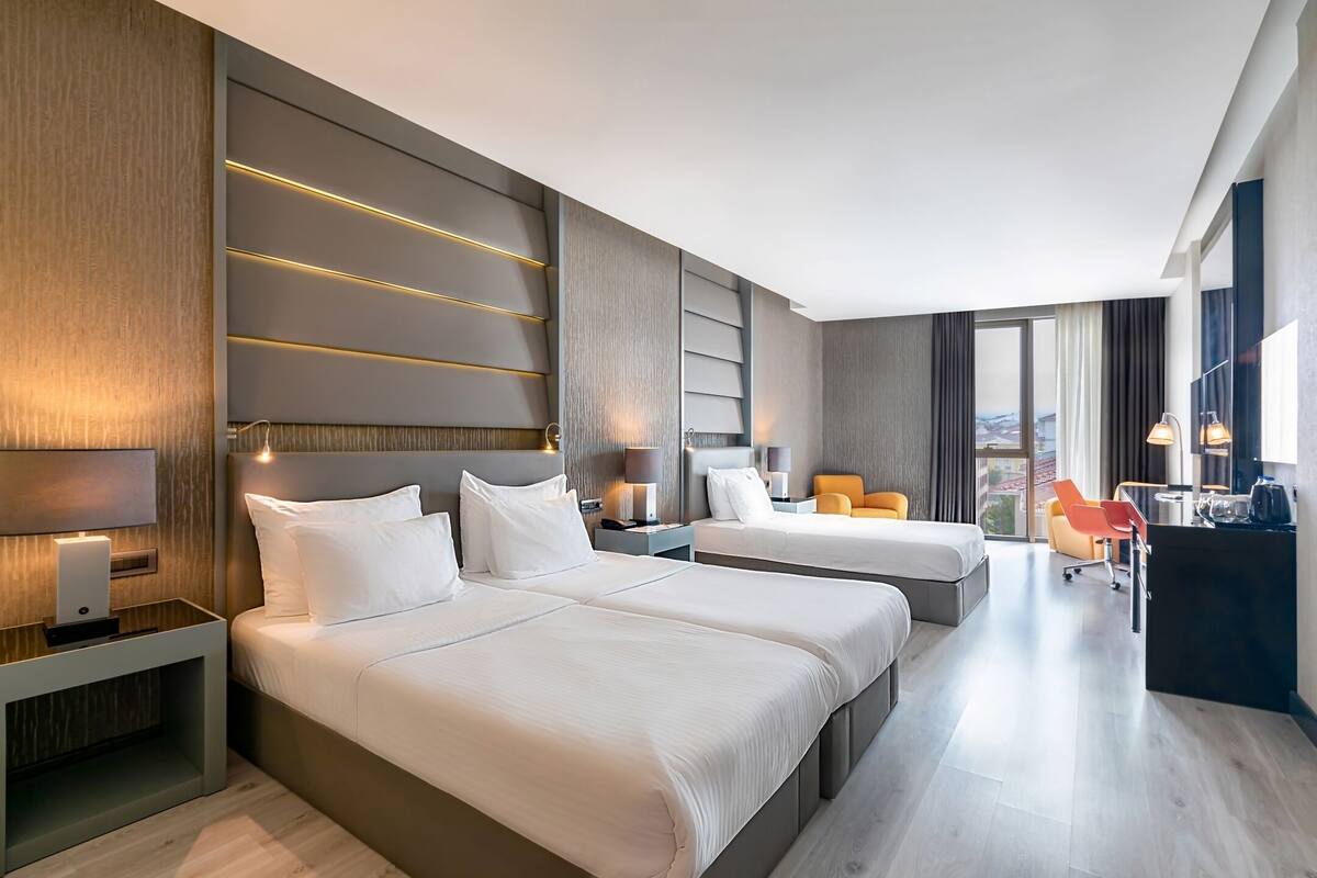 Una habitación de hotel moderna con dos camas, un escritorio y un área de descanso.