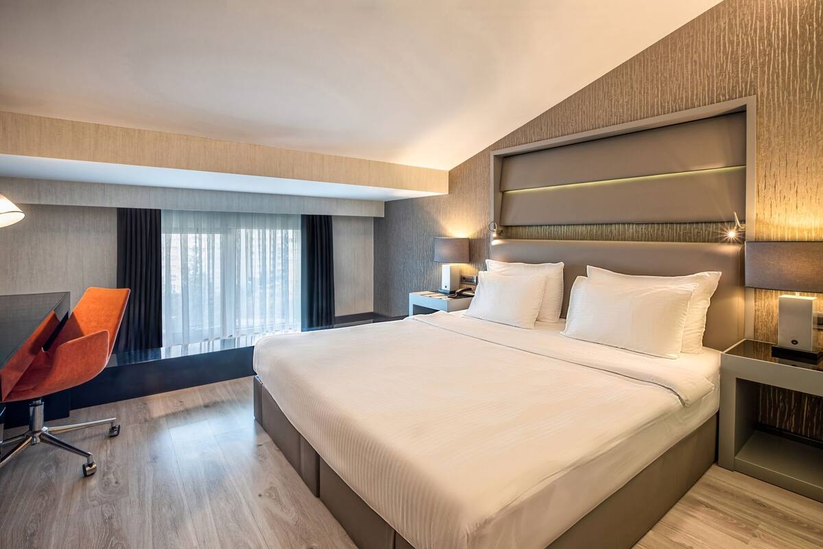 Una habitación de hotel moderna con una cama grande, un escritorio y una silla.