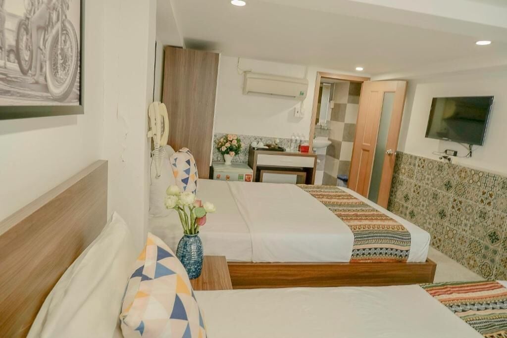 Une chambre d’hôtel avec deux lits, une salle de bain, une télévision et un tableau au mur.