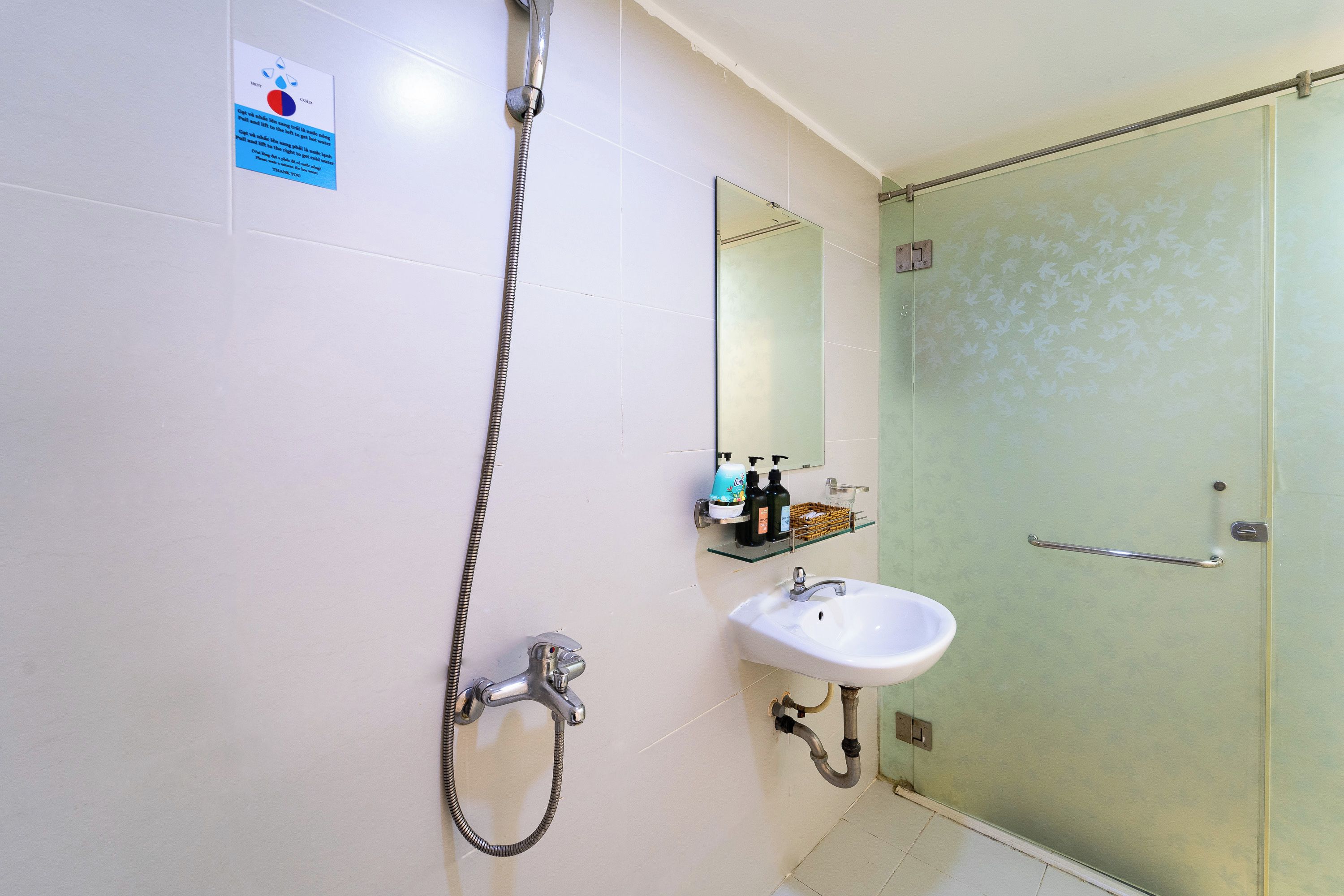 A bathroom with a shower, sink, and a glass-enclosed shower stall.